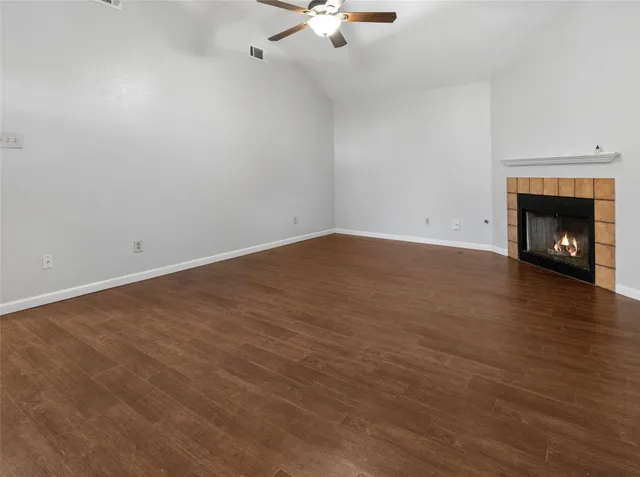 a view of an empty room with wooden floor fireplace and a window
