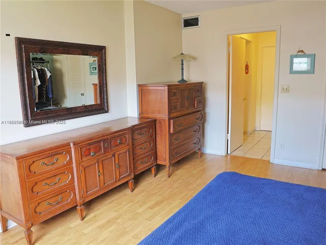 a view of a bedroom with wooden floor and cabinet