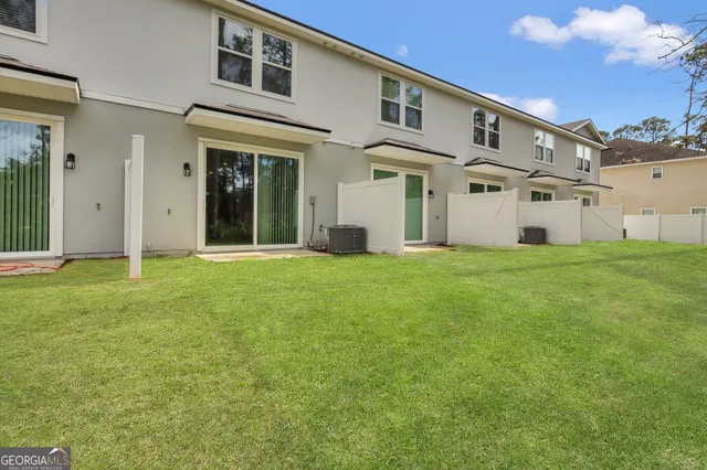 a view of a white house with a big yard and large trees