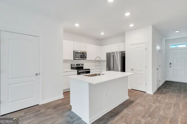 a kitchen with stainless steel appliances a refrigerator a stove a sink and white cabinets