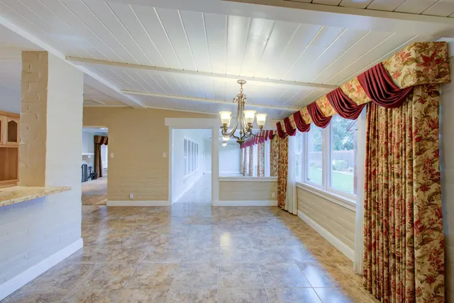 an empty room that has a window and chandelier fan