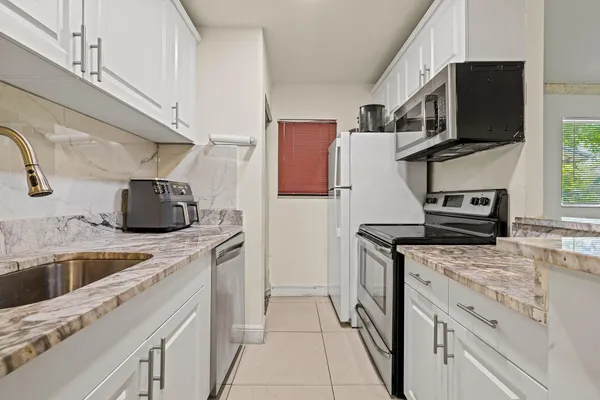 a kitchen with granite countertop a sink and steel appliances
