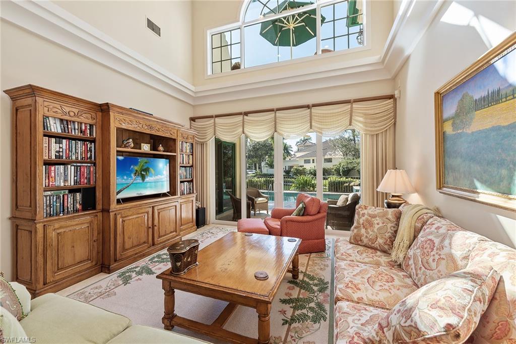 8063 Vizcaya Way Naples, FL 34108 - Photo 4 of 28 a living room with furniture a flat screen tv and a floor to ceiling window