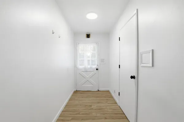 a view of a hallway with wooden floor and a bathroom