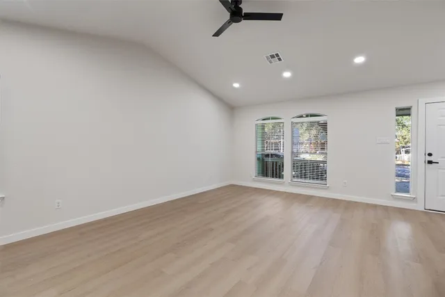 a view of an empty room with a window and wooden floor