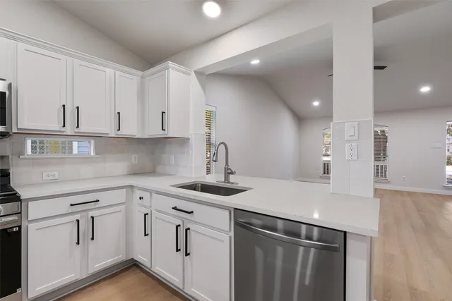 a kitchen with white cabinets sink and appliances