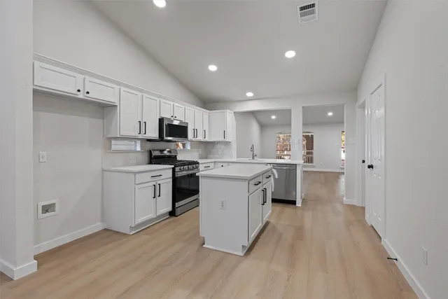 a kitchen with a white cabinets and wooden floor