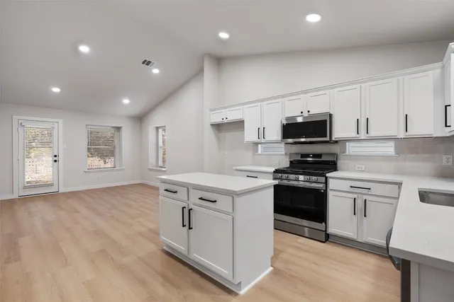 a kitchen with stainless steel appliances granite countertop a stove a sink and a microwave