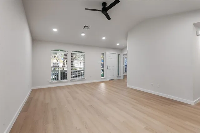 a view of an empty room with a window and wooden floor