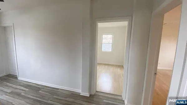 a view of an empty room with wooden floor and closet