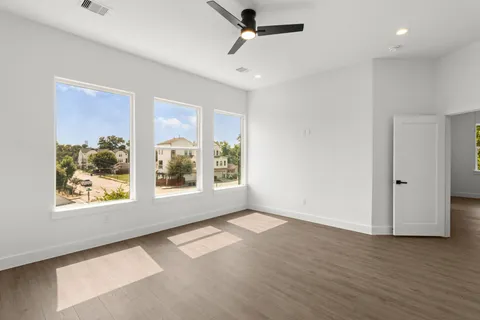 a view of an empty room with a window and wooden floor