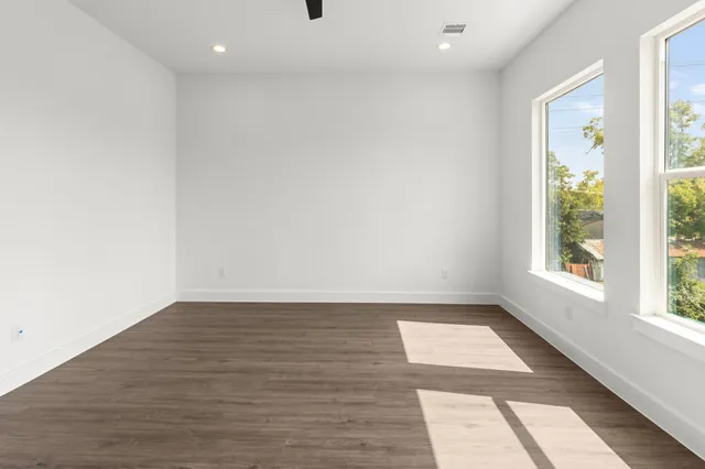an empty room with wooden floor and windows