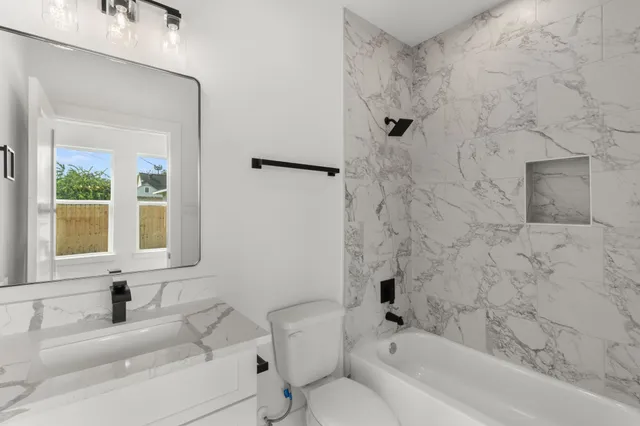 a bathroom with a granite countertop sink a toilet and a bathtub