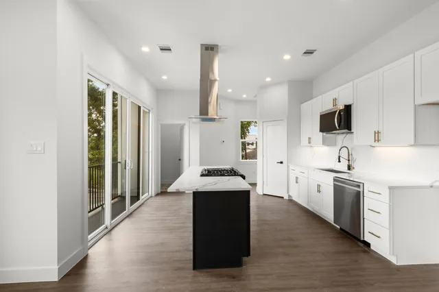 a kitchen with stainless steel appliances kitchen island granite countertop a stove a sink and a refrigerator