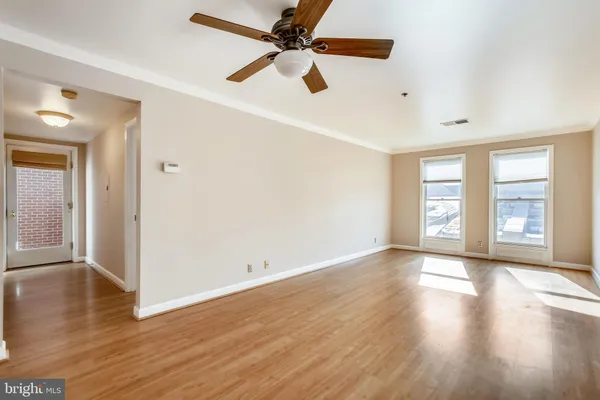 a view of an empty room with window and wooden floor