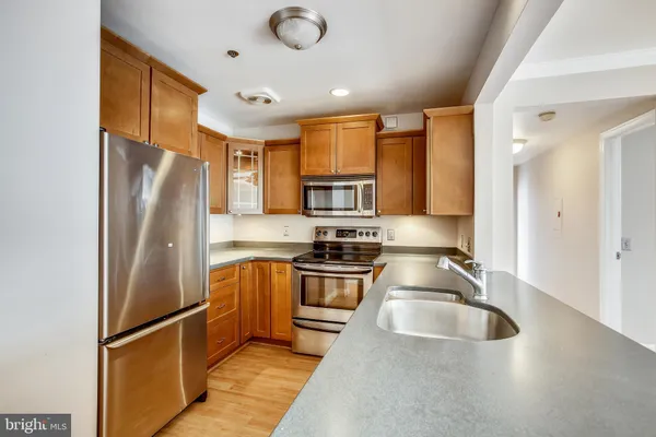 a kitchen with stainless steel appliances granite countertop a refrigerator a stove and a sink with wooden floors
