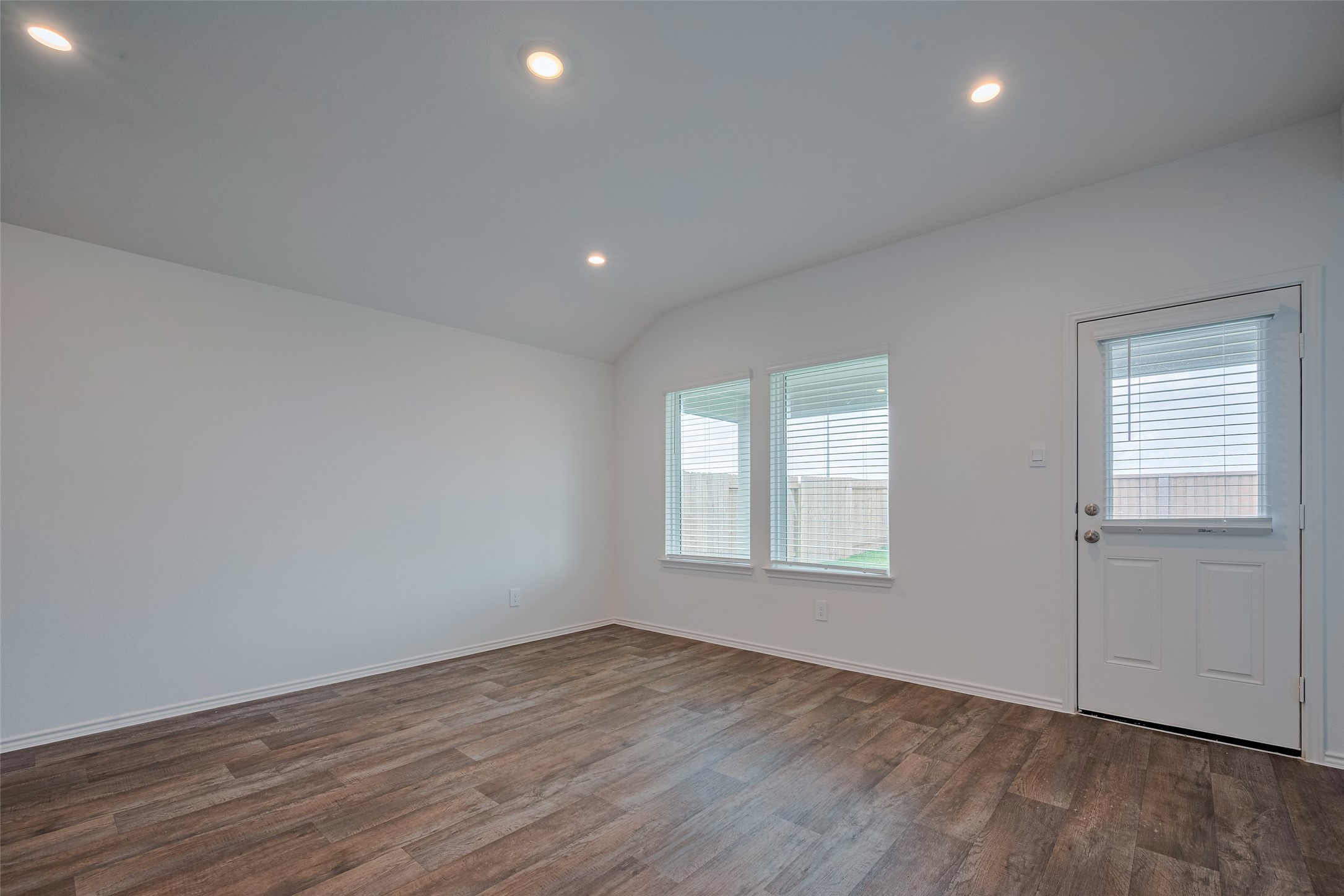 30910 Rockstock Road Fulshear, TX 77441 - Photo 9 of 33 Spacious and inviting family room with an open layout, wood-look flooring, and recessed lighting. Natural light pours in through the windows, creating a bright and airy space—perfect for relaxing or entertaining