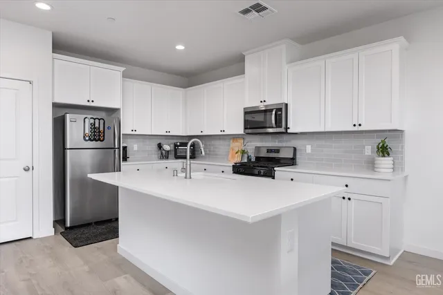 a kitchen with stainless steel appliances a stove a sink a refrigerator a microwave and cabinets