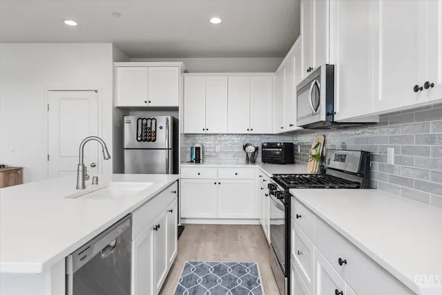 a kitchen with stainless steel appliances granite countertop a sink a stove and cabinets