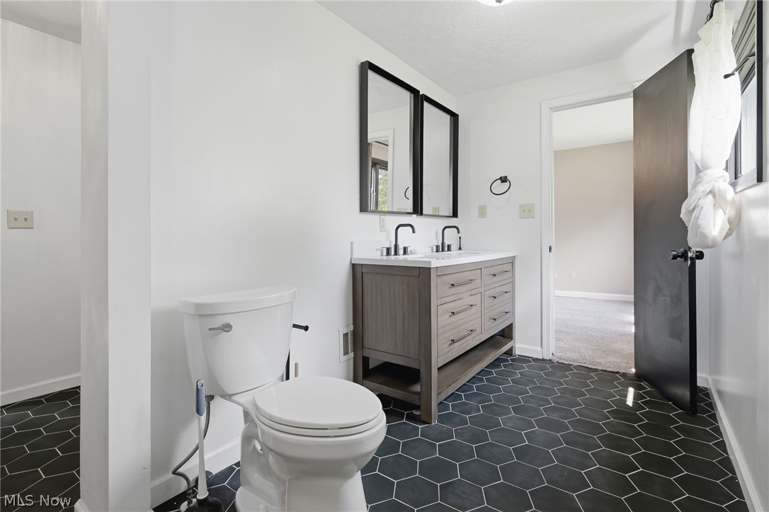 8160 Joyce Road Broadview Heights, OH 44147 - Photo 22 of 45 Bathroom featuring hexagonal dark floor tiling and a double vanity with stone-finish countertop