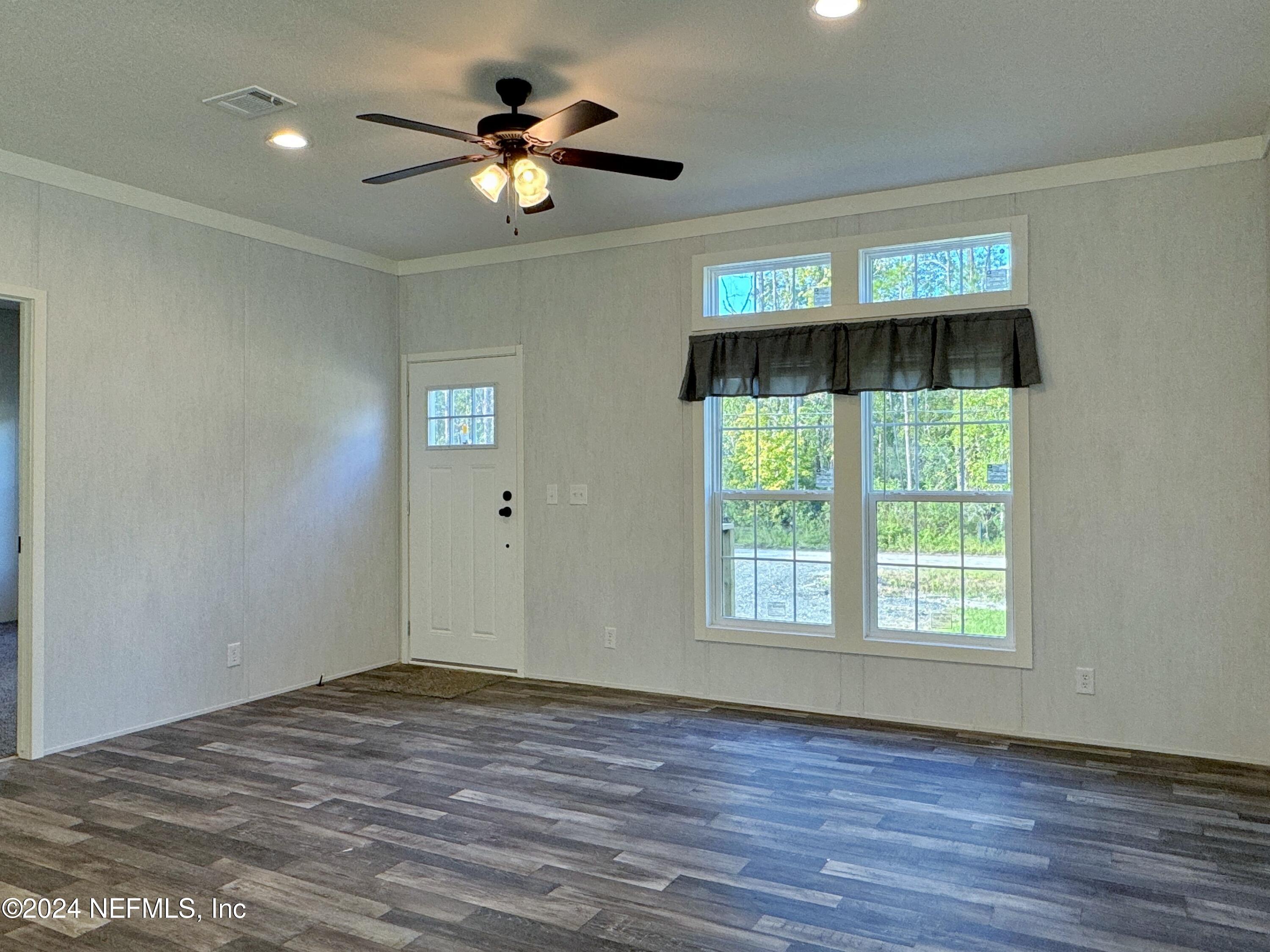 127 Domingo Road Satsuma, FL 32189 - Photo 8 of 18 an empty room with wooden floor chandelier fan and windows