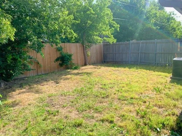 a view of backyard with tree and wooden fence