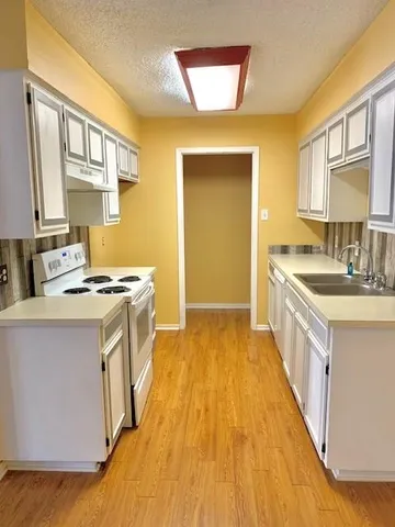 a kitchen with a sink stove top oven and a refrigerator