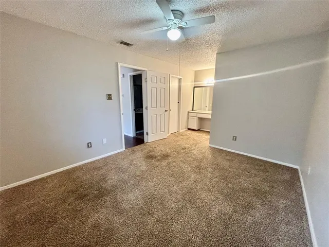 an empty room with a chandelier fan and windows