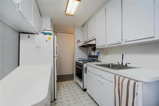 a kitchen with a sink a refrigerator and cabinets