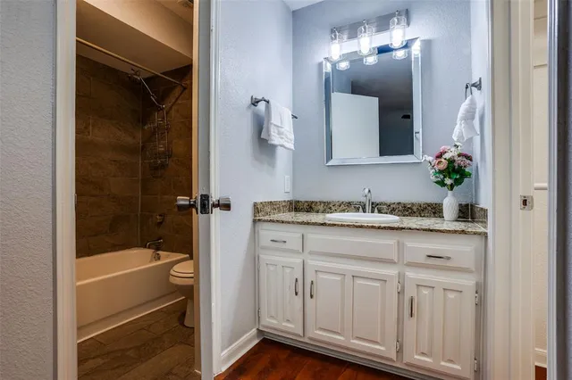 a bathroom with a granite countertop sink a mirror and a bathtub