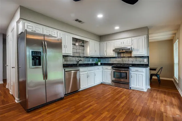 a kitchen with stainless steel appliances granite countertop a refrigerator and a stove top oven