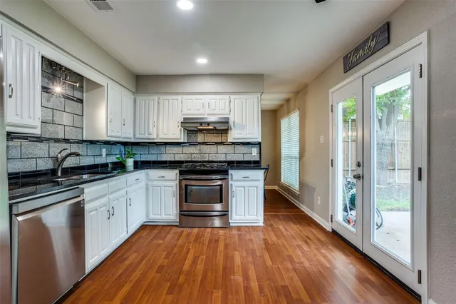a kitchen with kitchen island granite countertop wooden floors and white stainless steel appliances