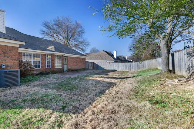 a view of a house with a yard and large tree