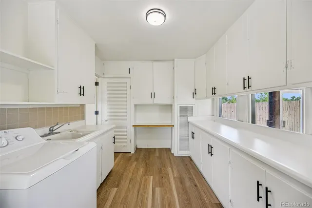 a large white kitchen with a lot of counter space and wooden floor