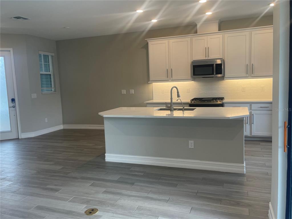 4596 Almada Lane Wesley Chapel, FL 33543 - Photo 5 of 56 a kitchen with kitchen island granite countertop a sink cabinets and stainless steel appliances