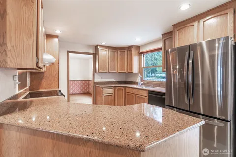 a kitchen with stainless steel appliances granite countertop a sink a stove and a refrigerator with wooden floor