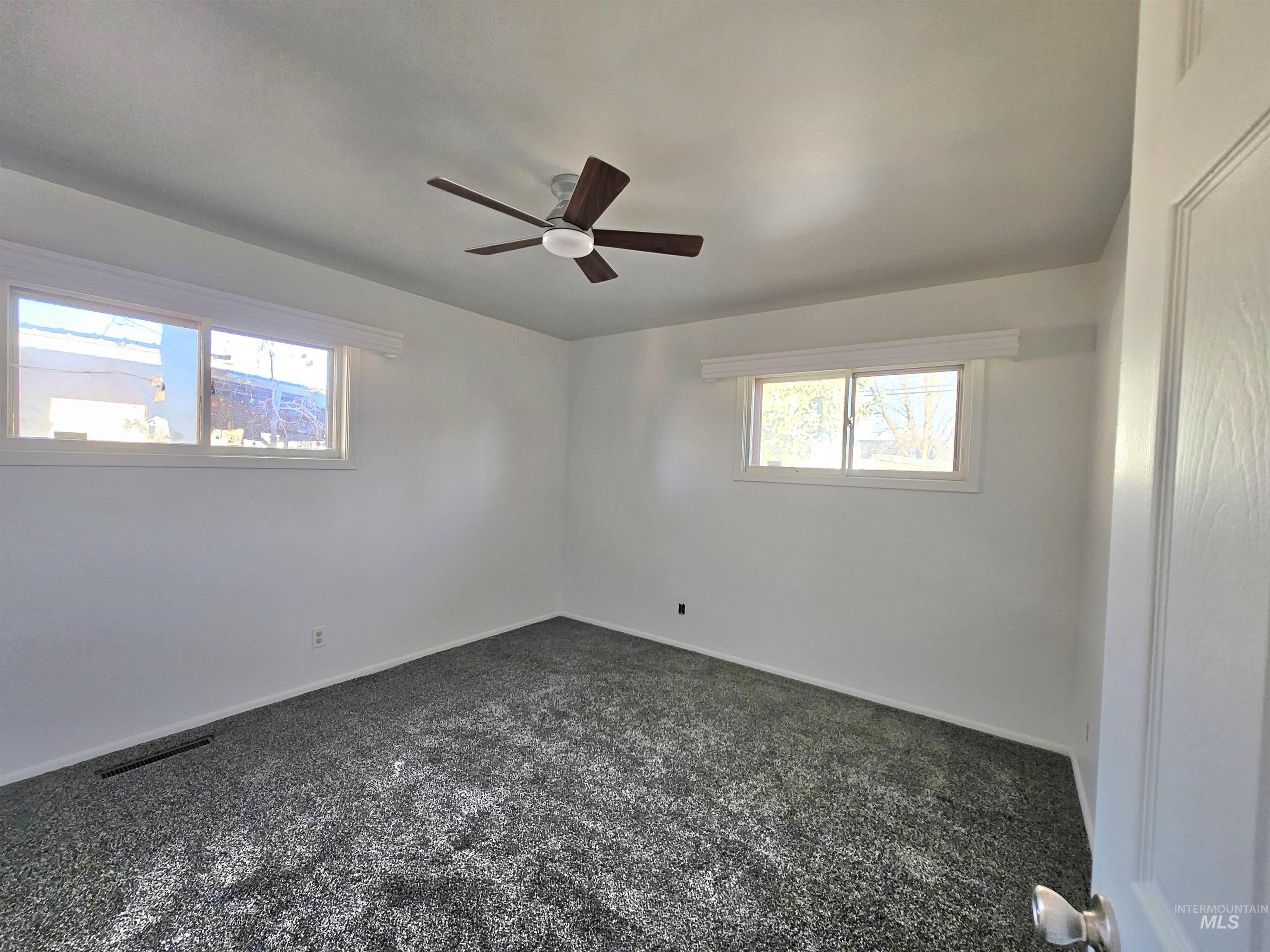 810 South D Street Rupert, ID 83350 - Photo 9 of 16 Empty room with dark carpet and ceiling fan