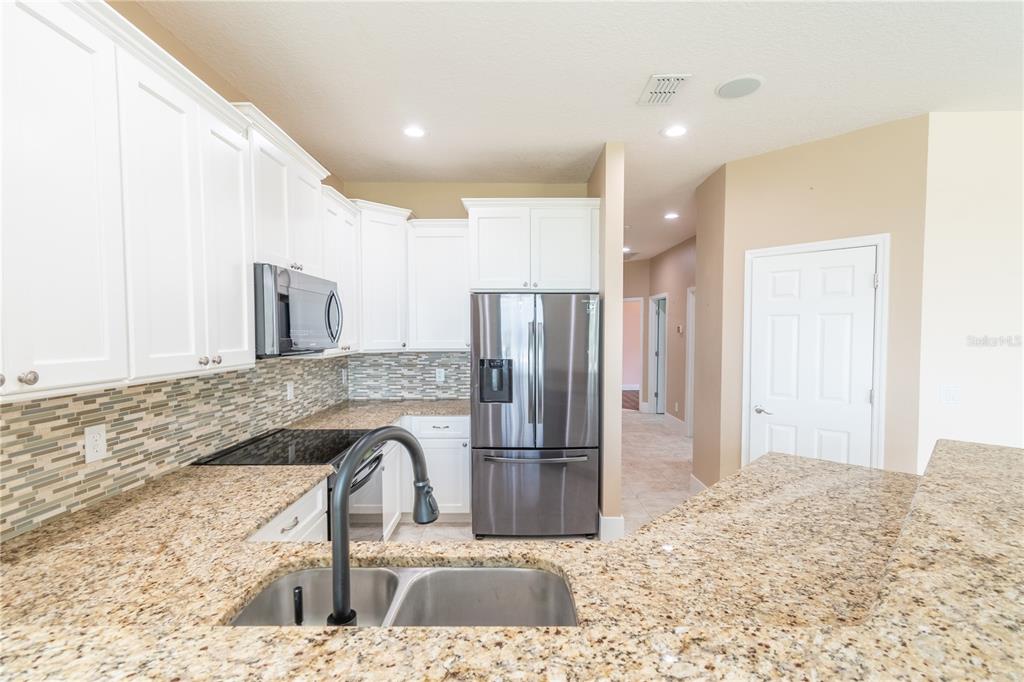 3862 Beacon Ridge Way Clermont, FL 34711 - Photo 31 of 56 a kitchen with granite countertop a refrigerator and a sink