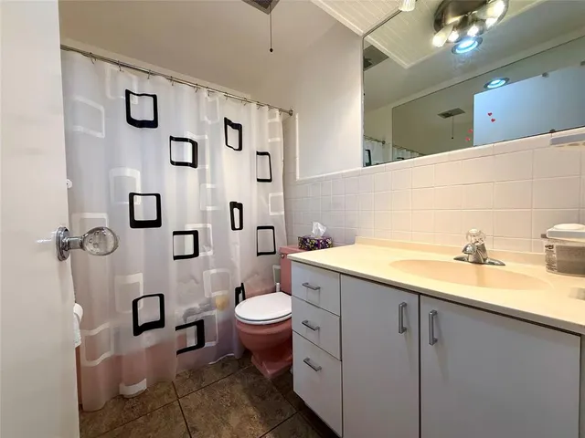 a bathroom with a granite countertop toilet sink and mirror