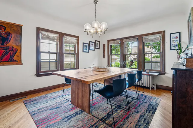 a dining room with wooden floor a chandelier a wooden table and chairs