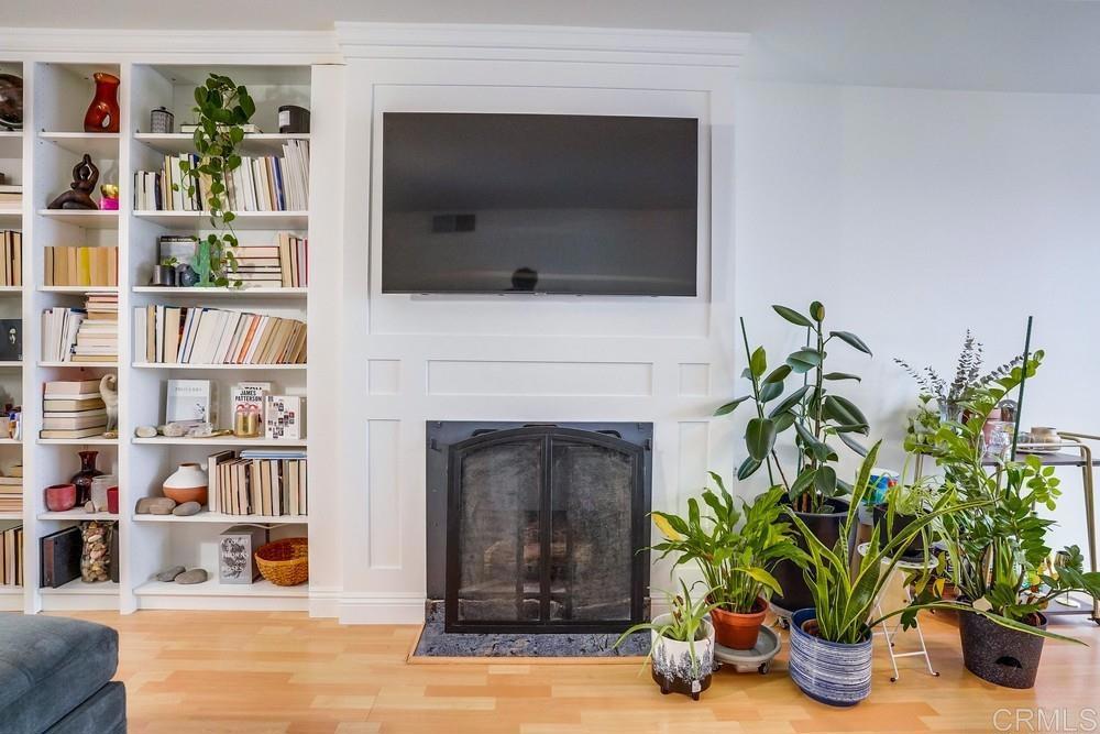 a living room with a bookshelf a potted plant and a fireplace
