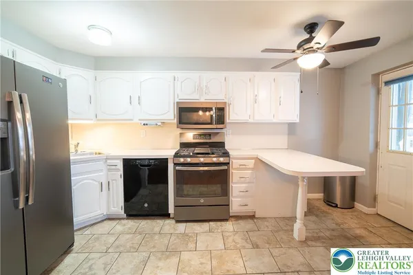 a large kitchen with granite countertop a stove a sink dishwasher and a refrigerator with wooden floor
