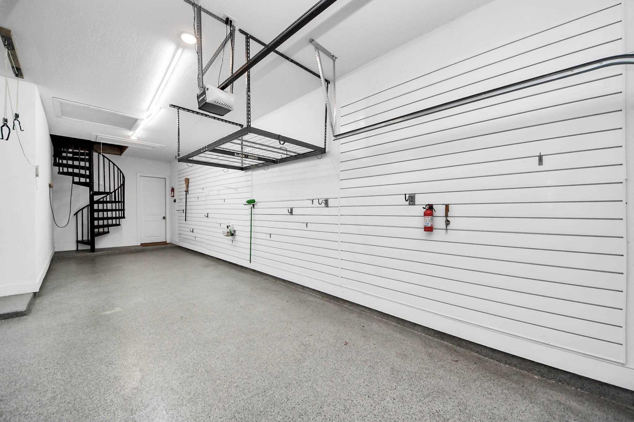 4310 Bakers Cove Manvel, TX 77578 - Photo 37 of 47 3 car tandem garage with epoxy flooring, wired for an EV charger on the wall between the two garage doors, plus room to add another charger on the left side wall from this view. Right wall has a slatboard system, you can see ceiling mounted racks and a bike pulley lift in view as well.
