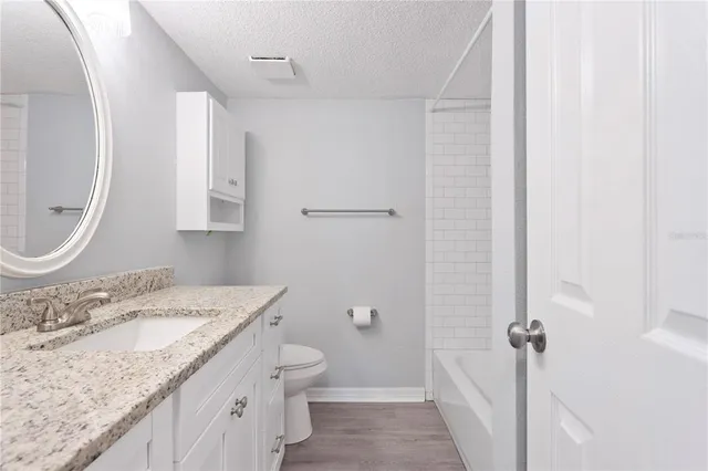 a bathroom with a granite countertop sink a mirror and a toilet