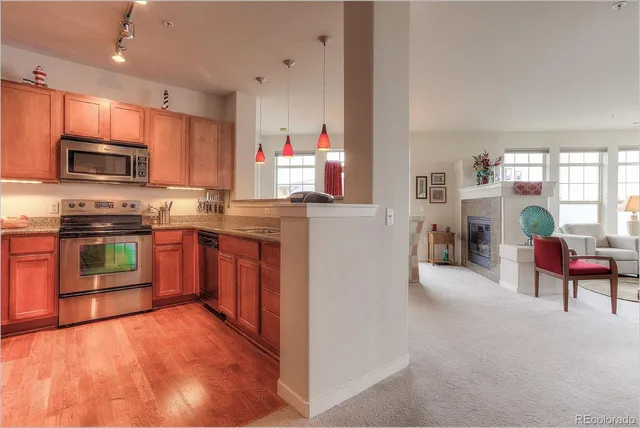 a kitchen with stainless steel appliances granite countertop a stove top oven a sink dishwasher a dining table and chairs with wooden floor