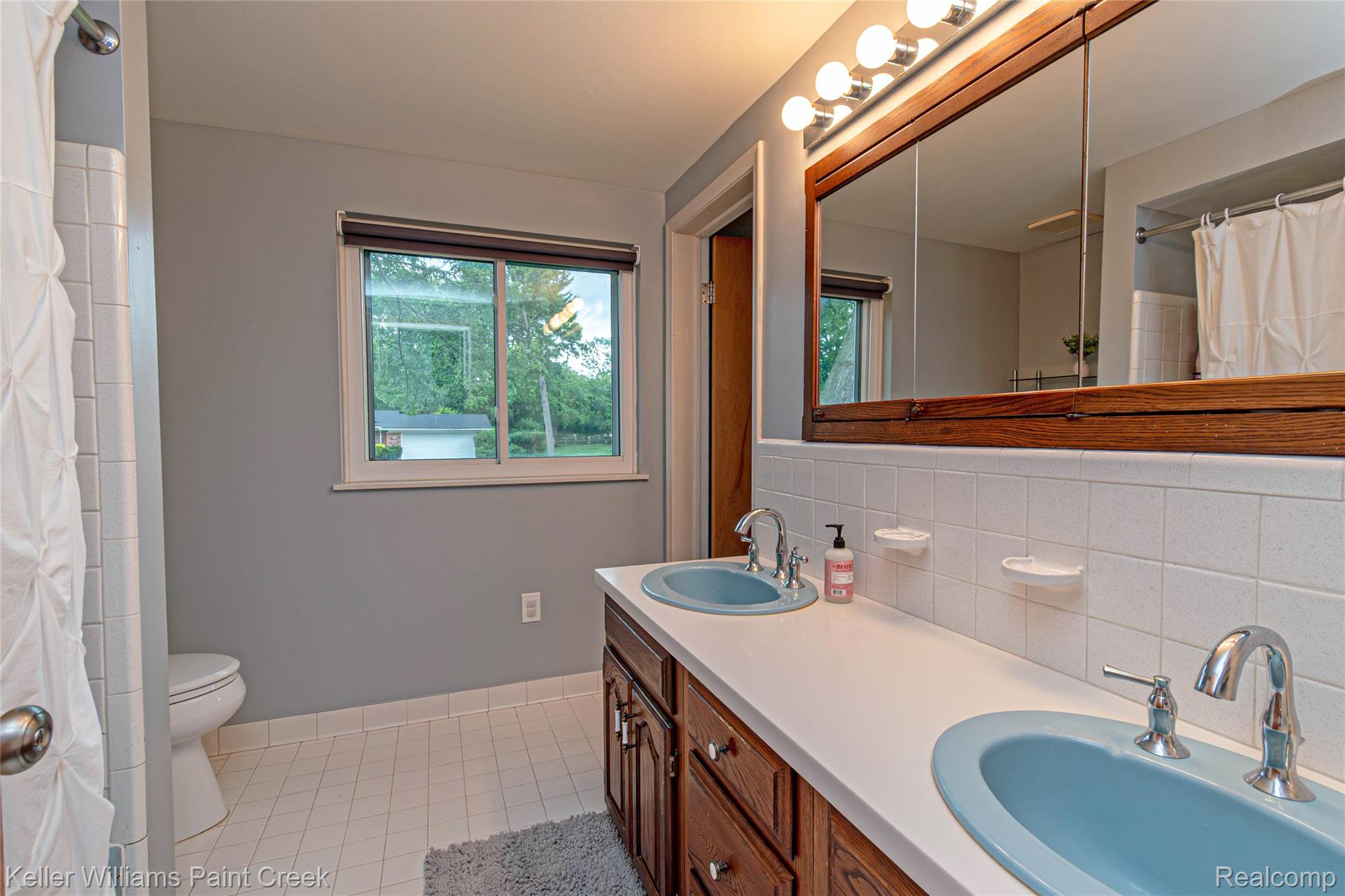 7093 Stonebrook Road West Bloomfield, MI 48322 - Photo 31 of 64 Bathroom featuring a double vanity with built-in wood cabinetry, light blue oval sinks, and a white countertop