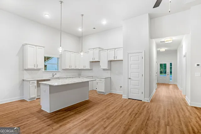 a large white kitchen with a sink a refrigerator and white cabinets