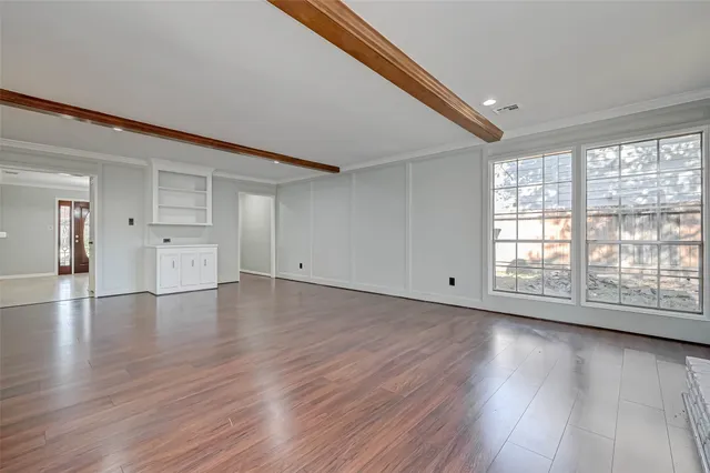 an empty room with wooden floor fan and window
