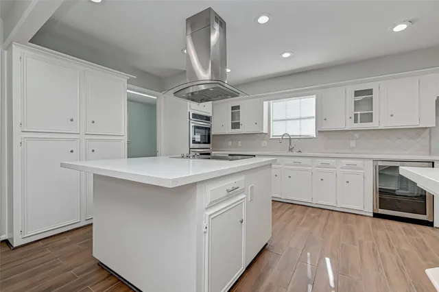 an empty room with wooden floor chandelier fan and windows