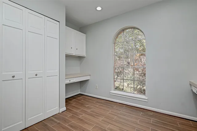 an empty room with wooden floor chandelier fan and windows